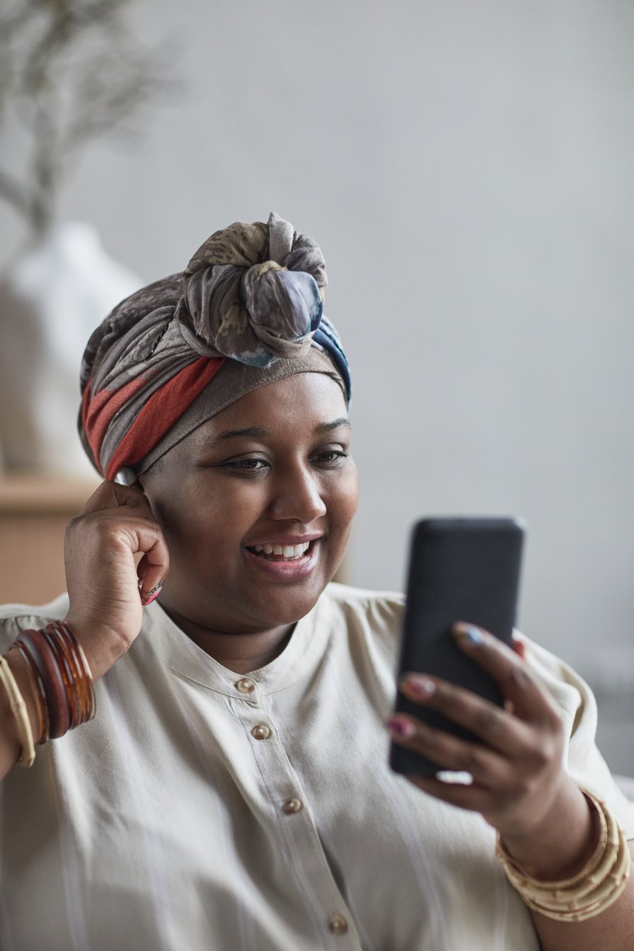 Woman with a Headwrap Looking at Her Cell Phone